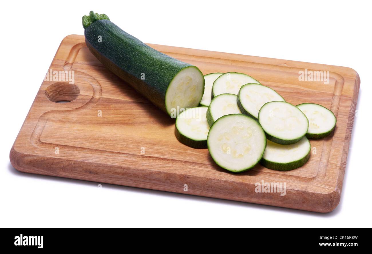 Sliced zucchini circles on wooden cutting board isolated on white background Stock Photo