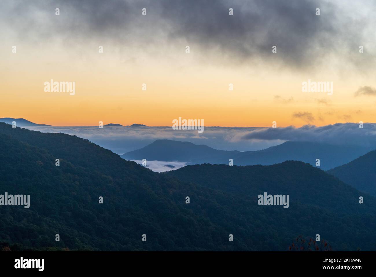 The sunset with clouds in the sky over hills in a beautiful valley ...