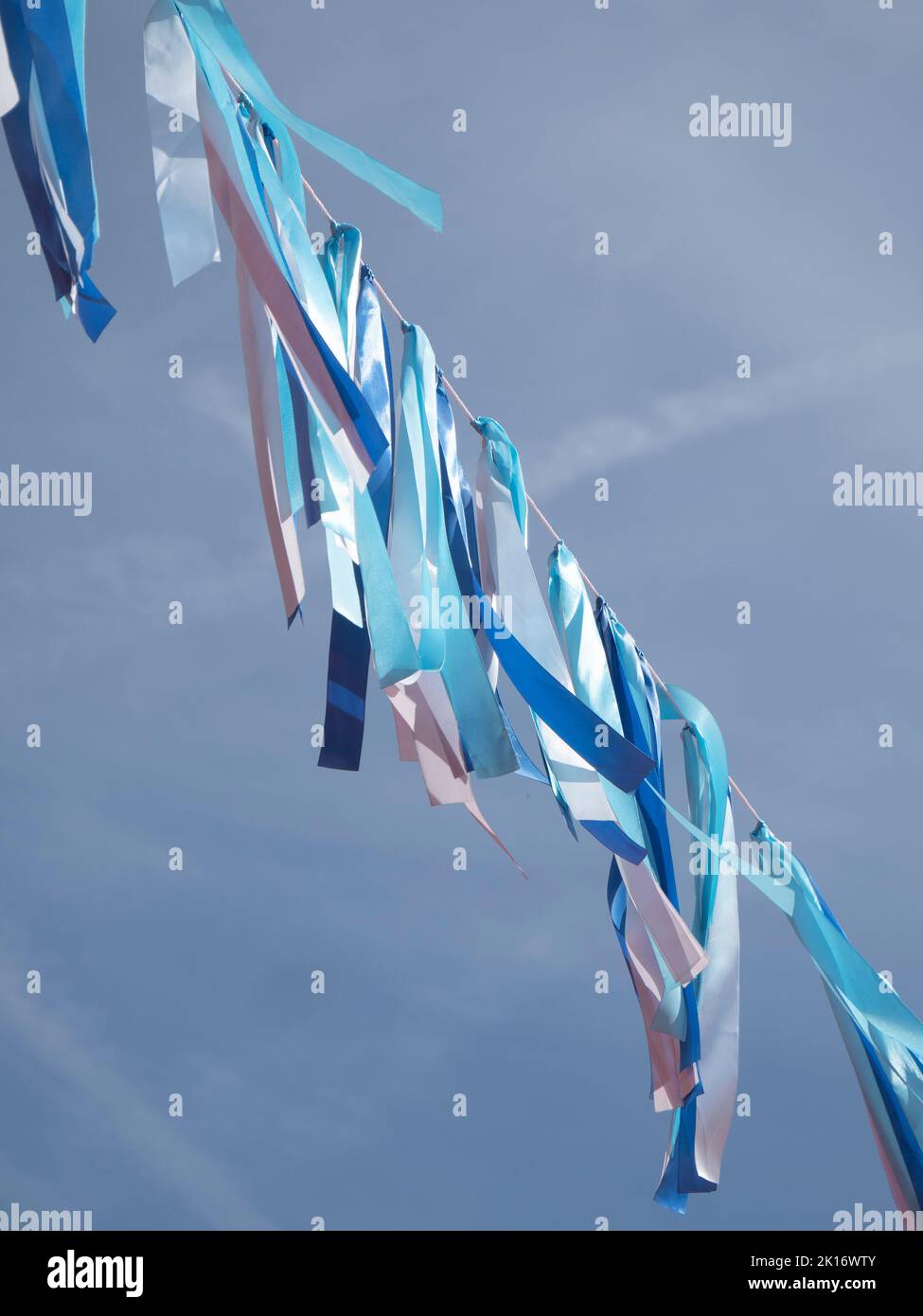 Vertical photo of a rope with blue colored ribbons from dark to light Stock Photo