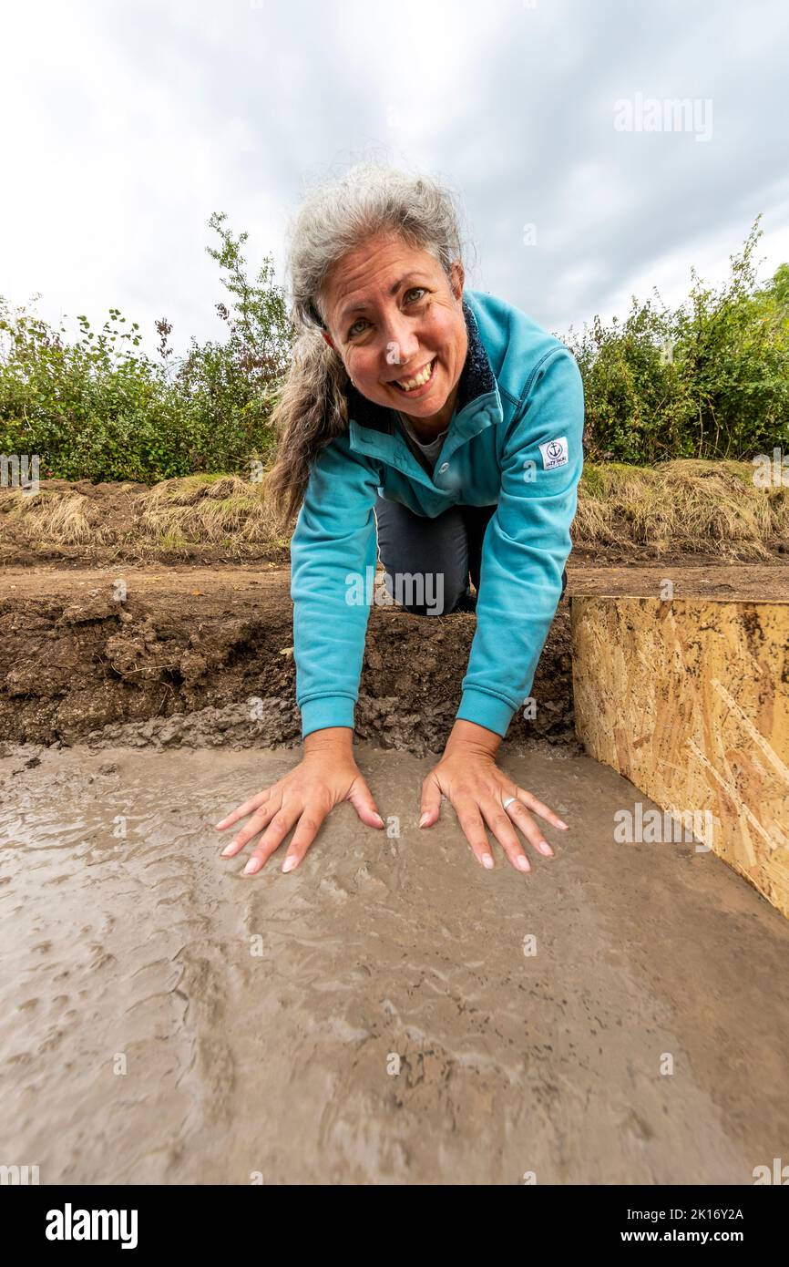 A woman leaves her handprints in a wet concrete footing to mark her ownership of new stables. Stock Photo