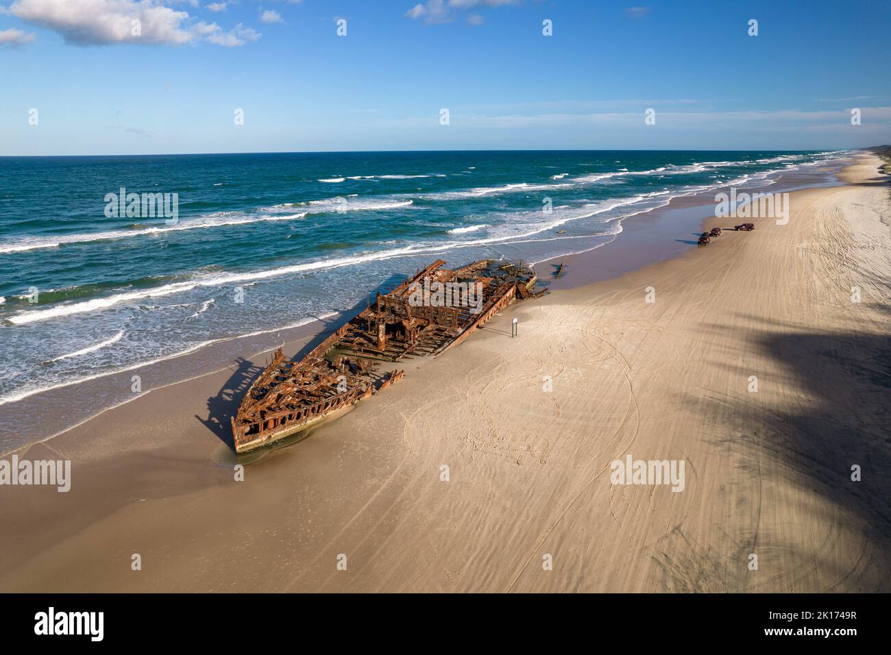 Landscape drone view of the Maheno shipwreck, Fraser Island (K'gari) off the coast of Queensland, Australia. The waves are rolling in behind the ship. Stock Photo