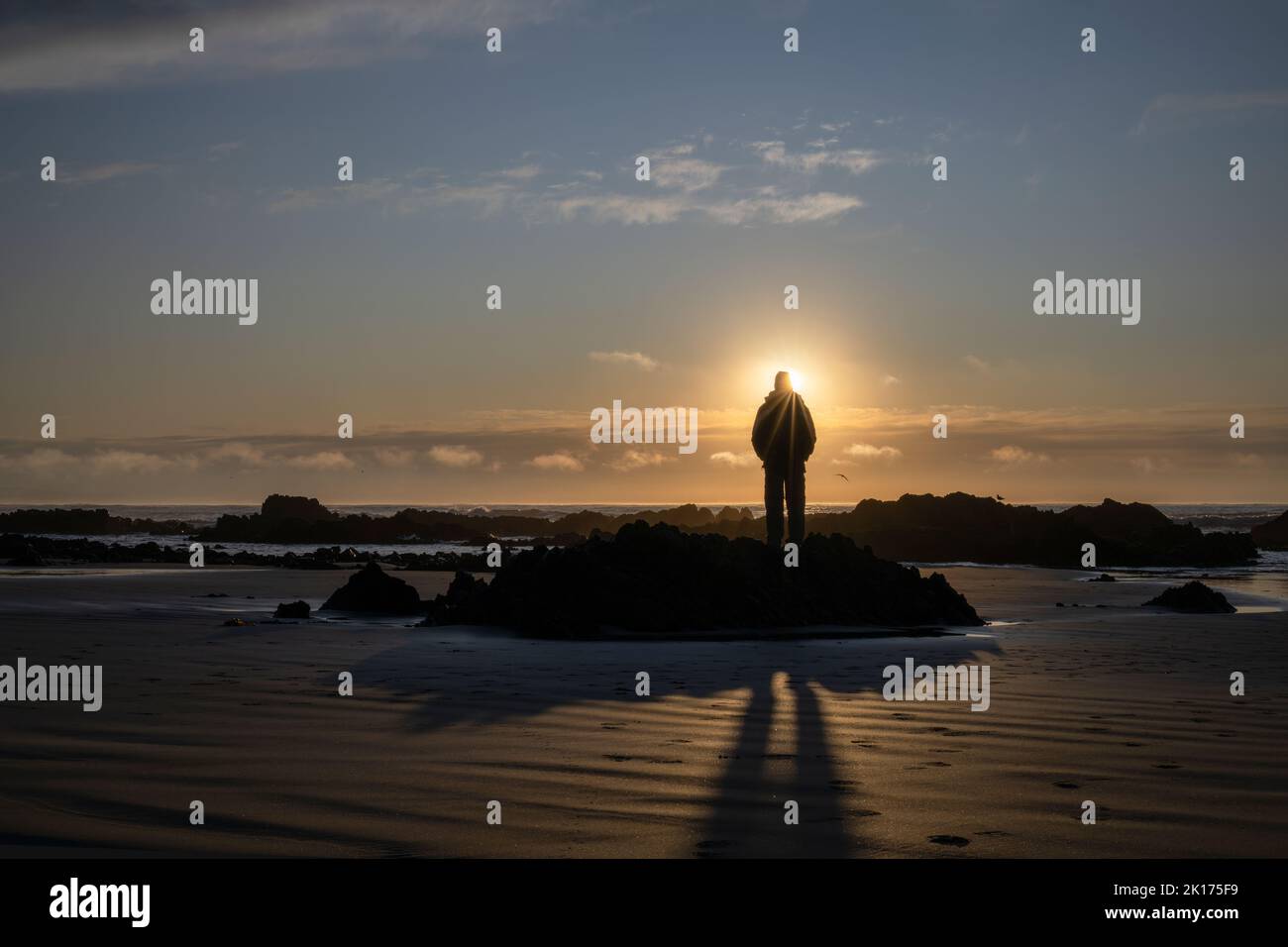 Man watching sunrise at a rocky beach.  Catlins, South Island. Stock Photo