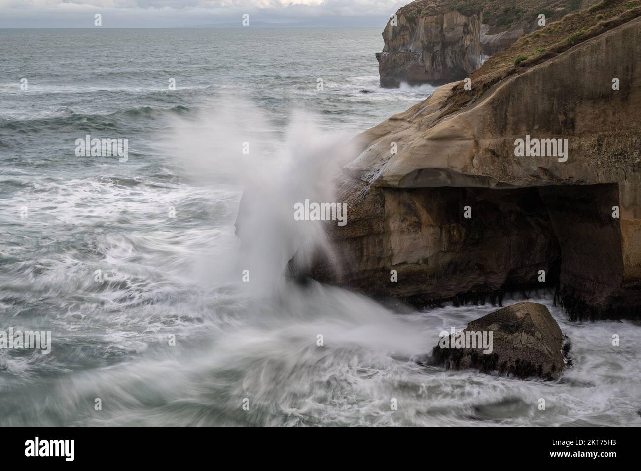 Waves splashing onto rocks at Tunnel Beach, Dunedin. Picture taken using slow shutter speed showing motion of the waves. Stock Photo