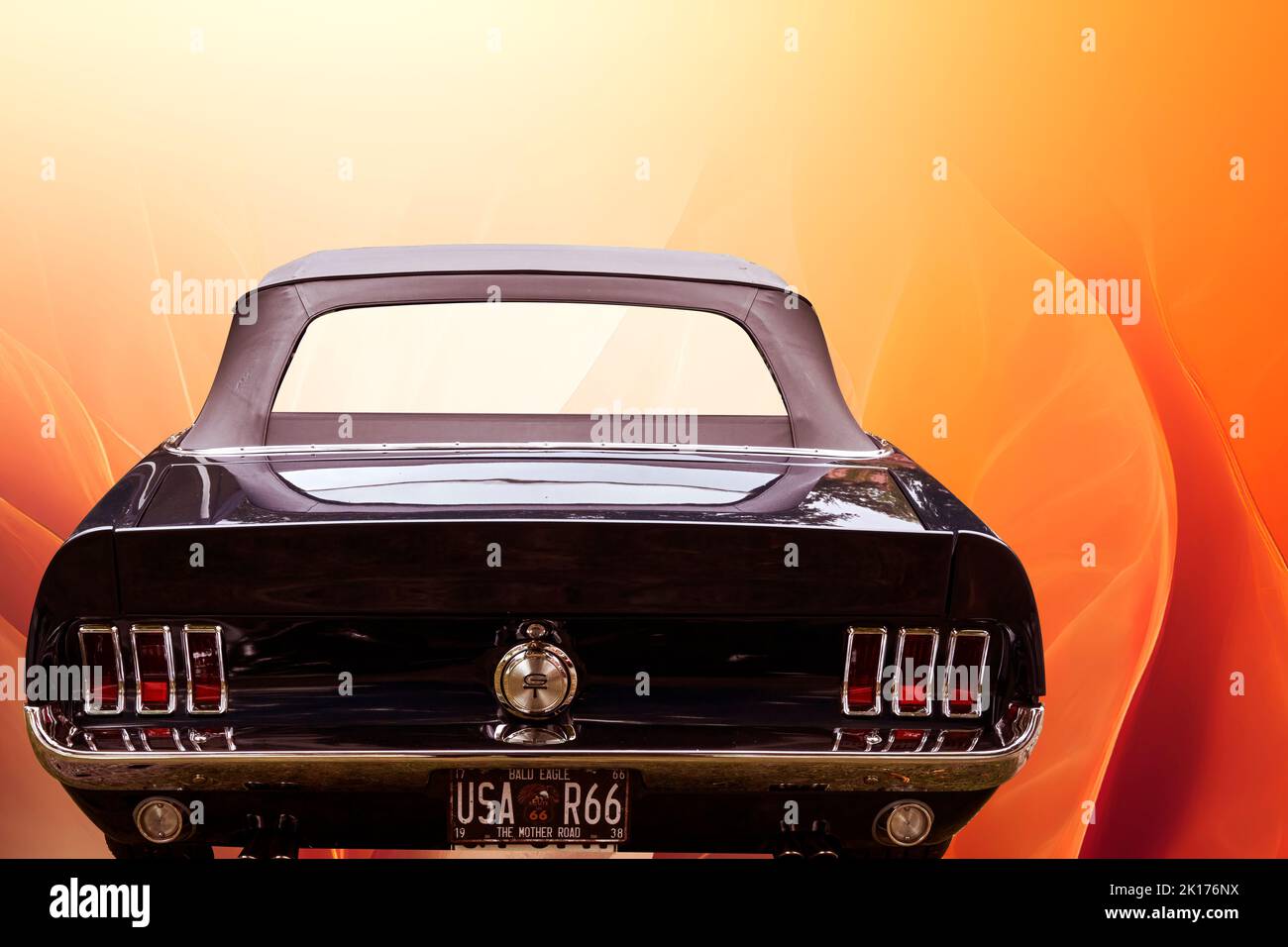 Ford Mustang rear view of dark painted American ponycar against surreal orange background , vehicle location Lehnin, Germany, September 11, 2022. Stock Photo