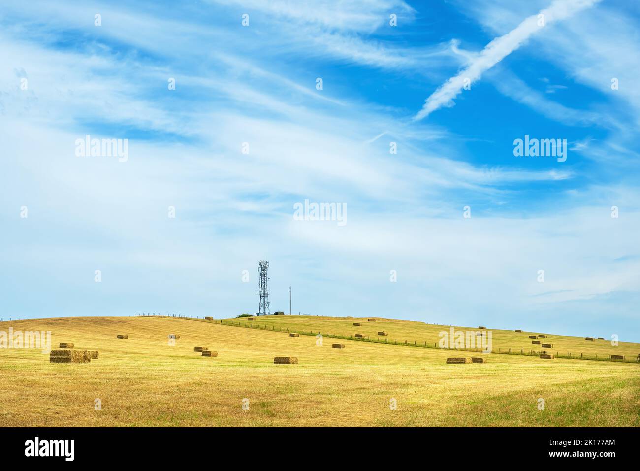 View to field on a hillside with hay bales and tower. Shropshire