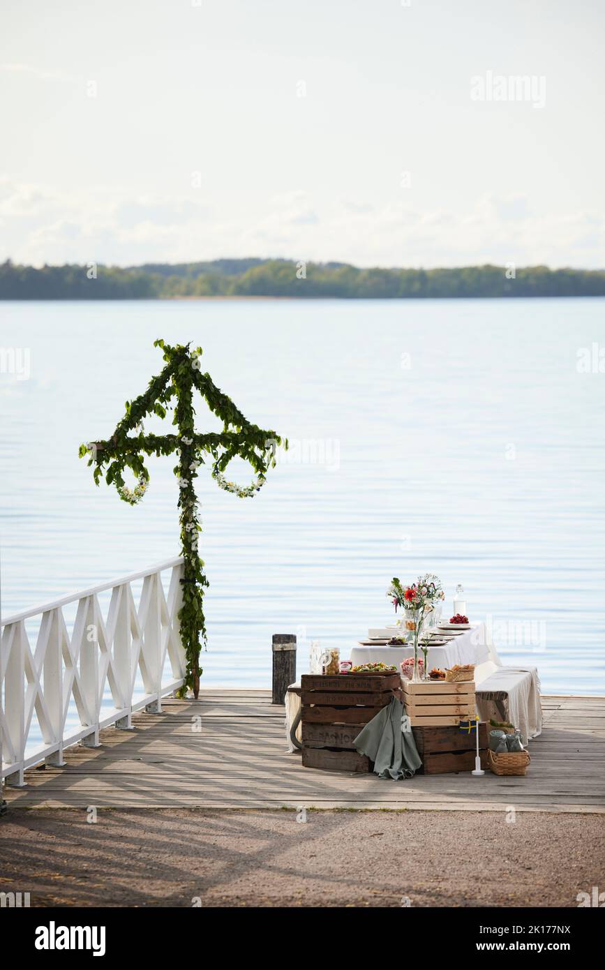 Table with midsummer meal at lake Stock Photo