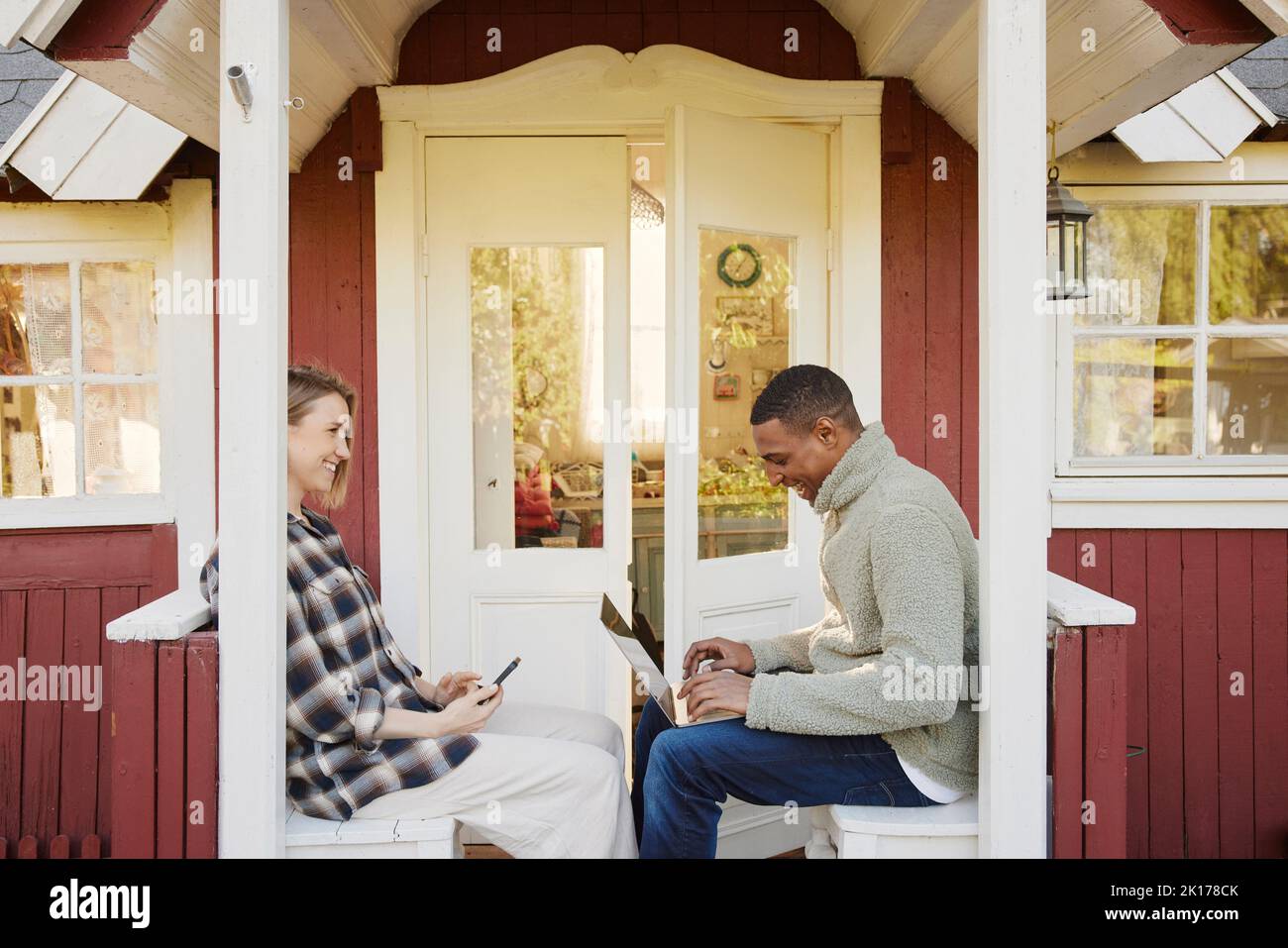 Couple sitting in front of wooden house Stock Photo