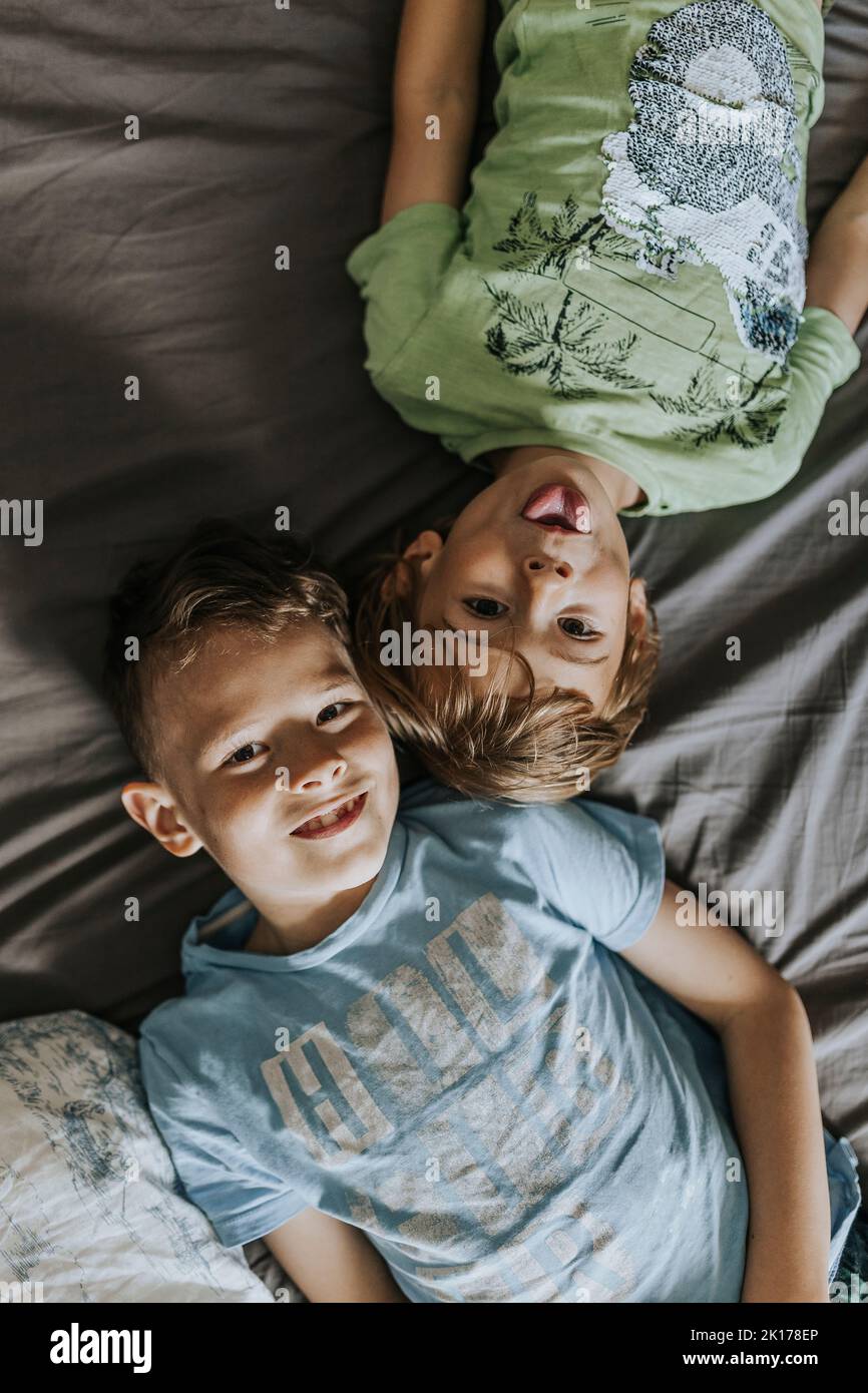 Portrait of brothers lying on bed Stock Photo