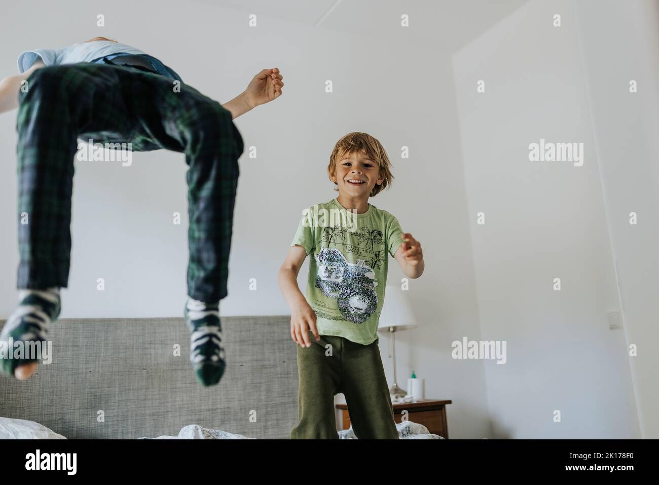 Brothers jumping on bed at home Stock Photo