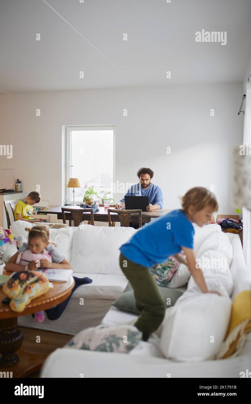 Children playing while father working from home Stock Photo