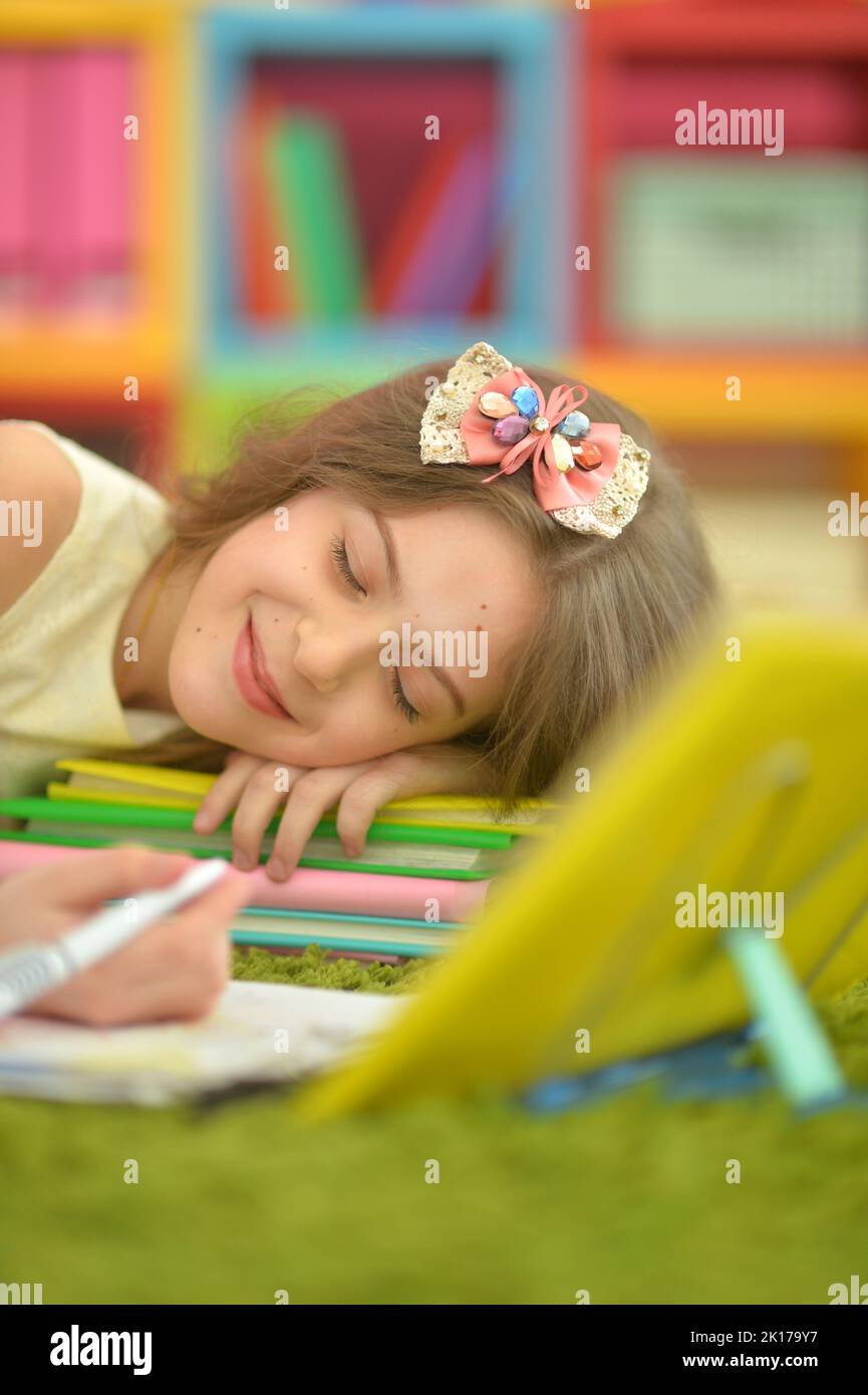 Beautiful little girl does homework and lies on carpet Stock Photo - Alamy