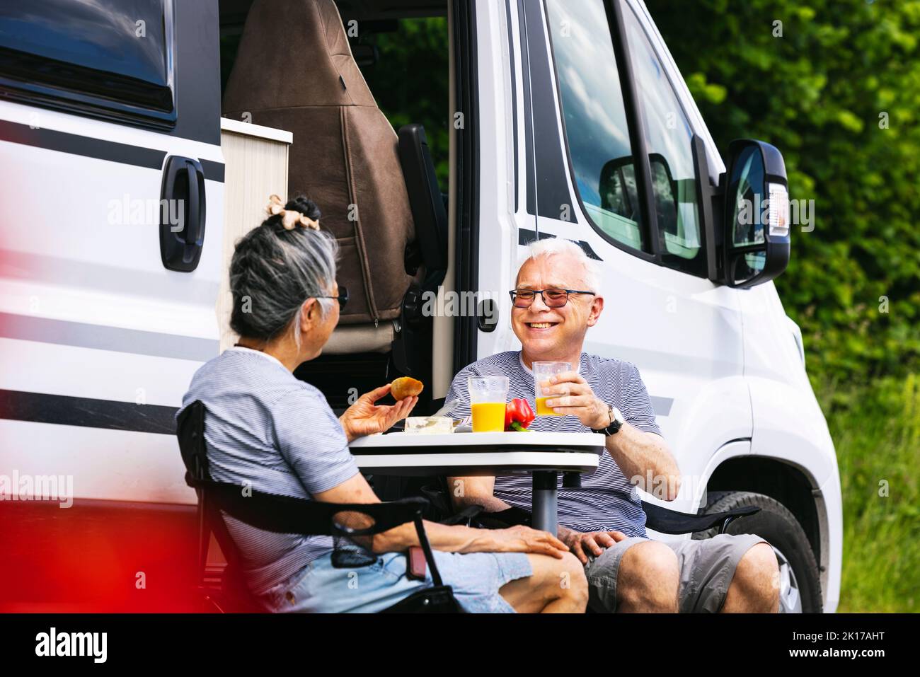 Senior couple sitting in front of trailer Stock Photo