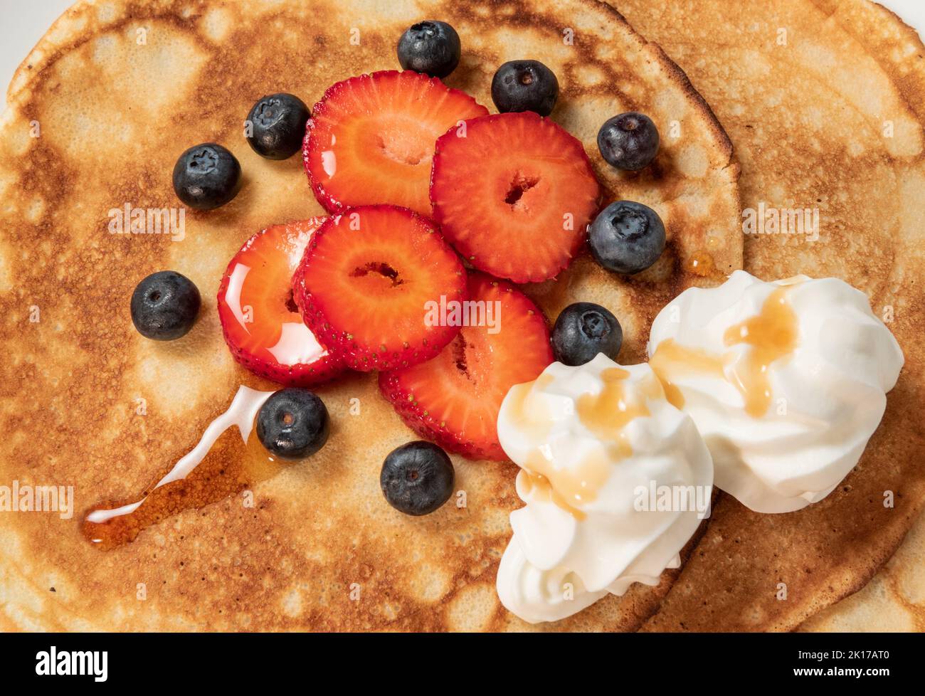 Pancakes with strawberries, blueberries, cream and syrup Stock Photo