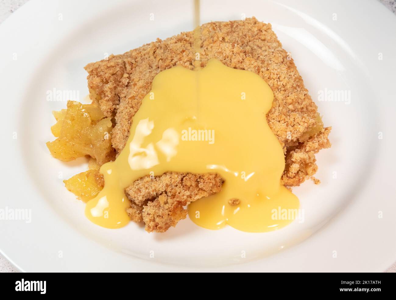 Apple crumble and pouring custard Stock Photo