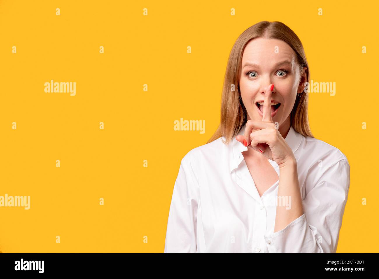 Female secret. Hush silence. Special offer. Keep quiet. Portrait of enthusiastic amazed surprised woman in white shirt showing shhh with finger at ope Stock Photo