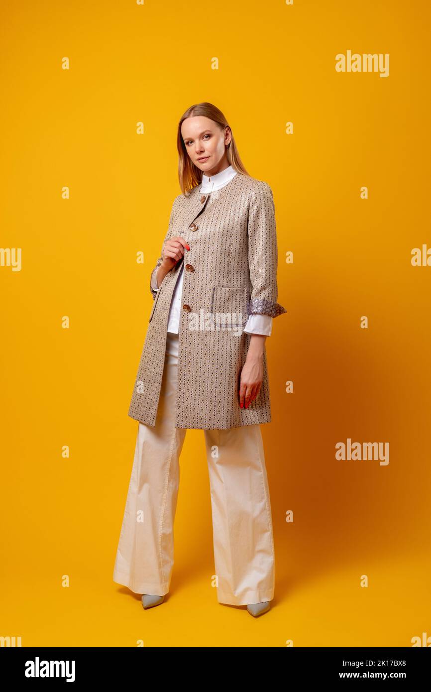 Woman fashion. Fall collection. Business look. Female individuality. Confident model in stylish beige smart casual outfit standing isolated on orange Stock Photo