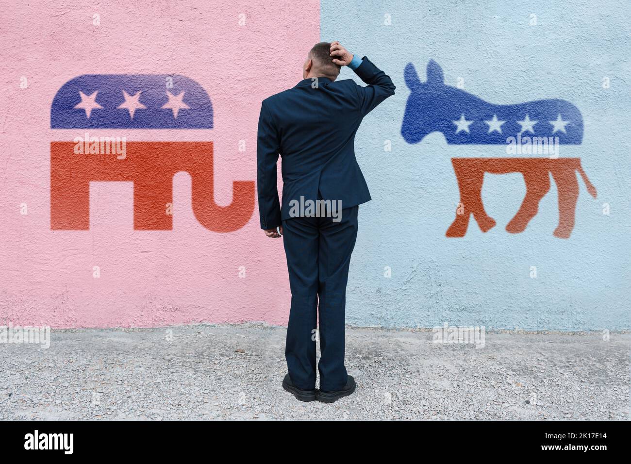 man thinks in the background wall with symbols of US parties. In American politics US parties are represented by either the democrat donkey or republi Stock Photo