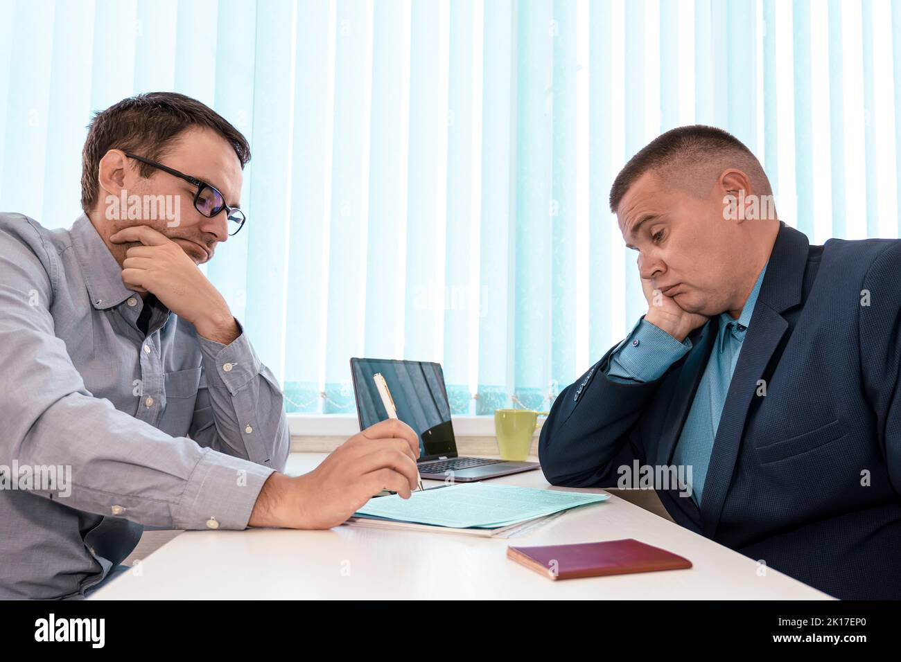 Focused young male ceo executive manager communicating with partner or client. Concentrated two businessmen sitting at table, involved in serious nego Stock Photo
