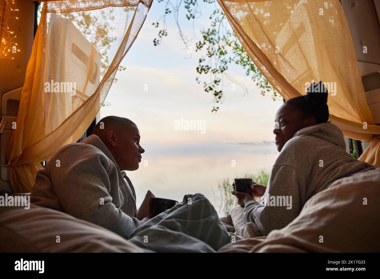 Young couple relaxing in camper van and looking at lake Stock Photo - Alamy