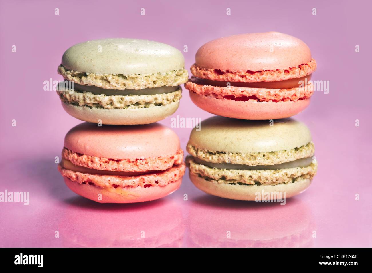 Stack of tasty french macarons on a pink pastel background. Stock Photo