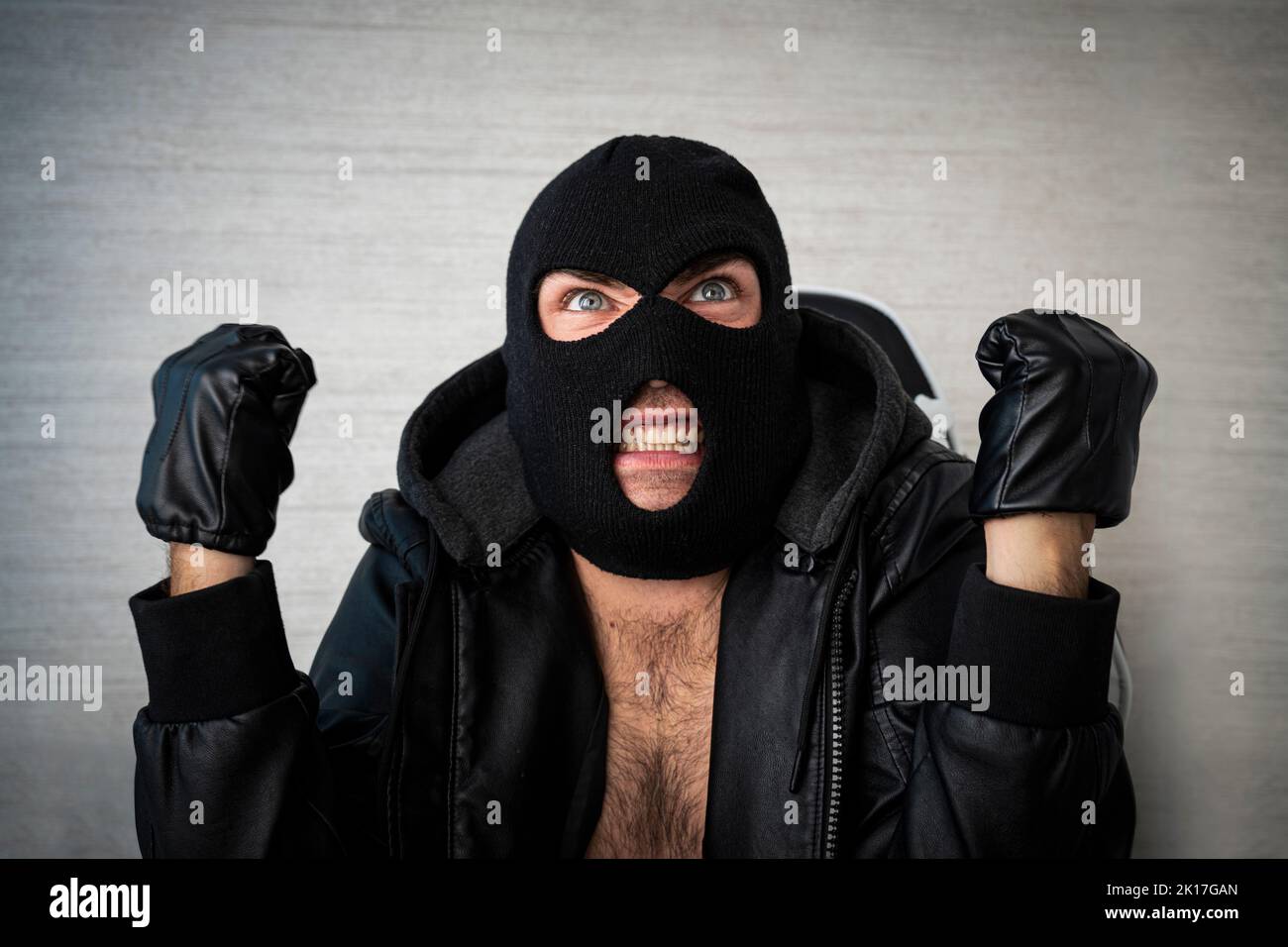 An angry aggressive masked thug screams in anger. Stock Photo