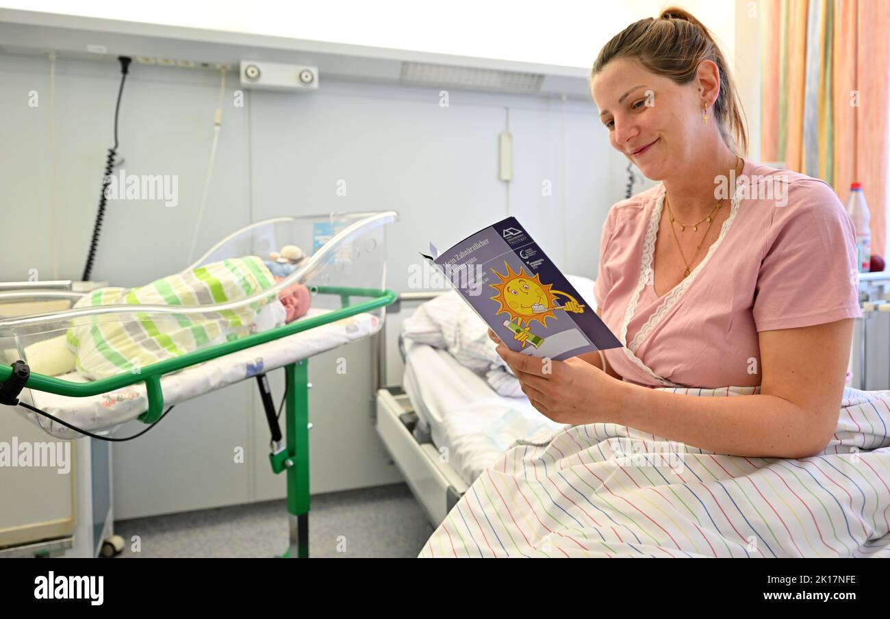 Nordhausen, Germany. 16th Sep, 2022. Anna Kellermann with her newborn son Louis leafs through a children's dental passport in the maternity ward of Südharz Klinikum Nordhausen. Since the summer of 2012, every newborn baby has been given a children's dental passport. In this passport, dentists document all check-ups and preventive measures in the dental practice, kindergarten and school during the first years of a child's life. Credit: Martin Schutt/dpa/Alamy Live News Stock Photo