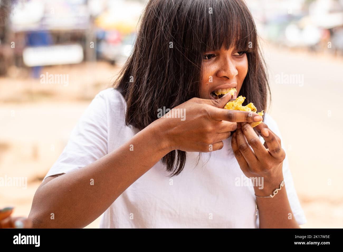 african woman is eating roasted plantain Stock Photo