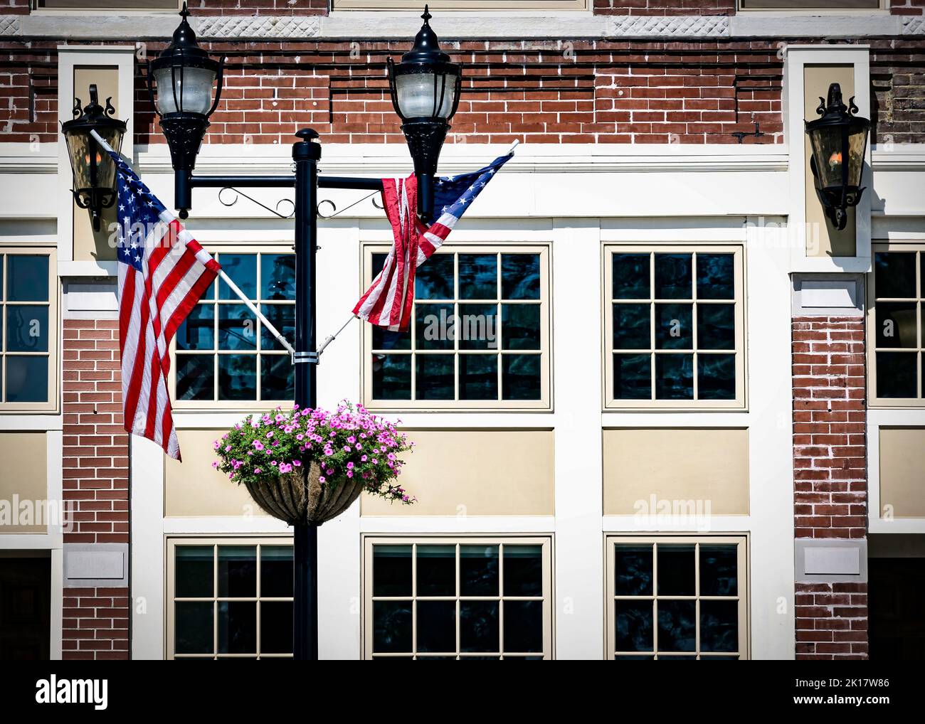 The flags and flowers on a light pole sitting on a city street in Manitowoc, Wisconsin. Stock Photo