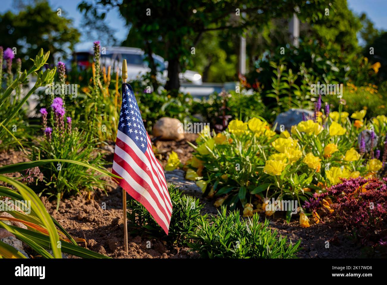 The morning sun shines on an American flag that stands in a flowerbed on the Mariners Trail between Manitowoc and Two Rivers, Stock Photo