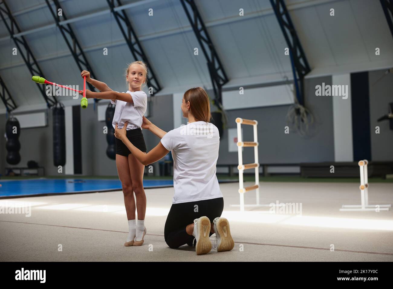 Little girls, beginner gymnastics athletes doing exercises with gymnastics equipment at sports gym, indoors. Concept of studying, achievements, skills Stock Photo