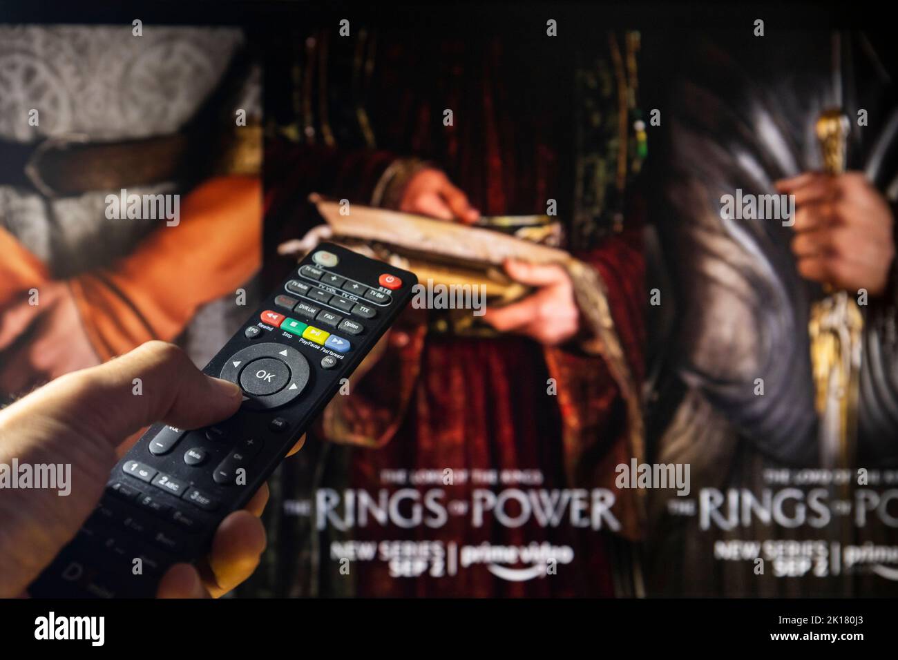 Belgrade, Serbia - September 12, 2022: The Lord of the Rings: The Rings of Power TV series on TV with remote control in hand. Focus on the remote cont Stock Photo
