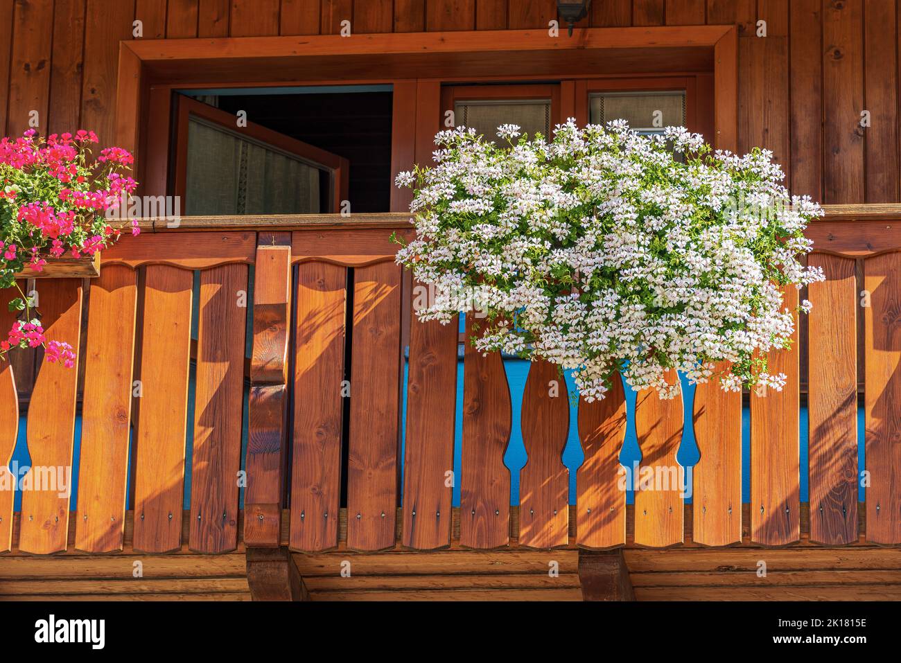Wooden balcony with white and red geranium flowers. Small village of Malborghetto-Valbruna in Val Canale, Udine, Friuli-Venezia Giulia, Italy, Europe. Stock Photo