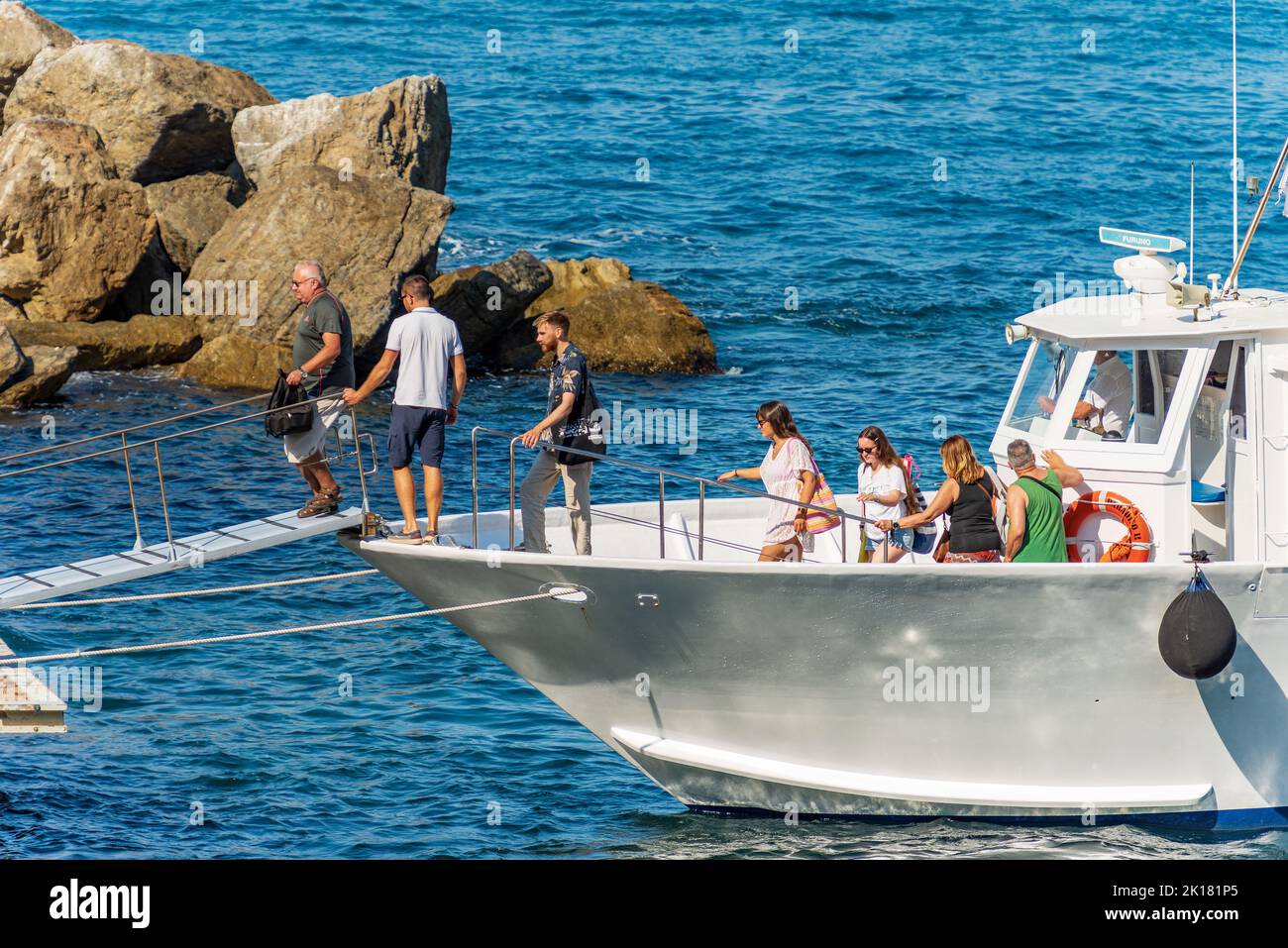 Group of Tourists Get Off a Small Ferry in the small port of the ancient village of Tellaro, Lerici, Gulf of La Spezia, Liguria, Italy. Stock Photo