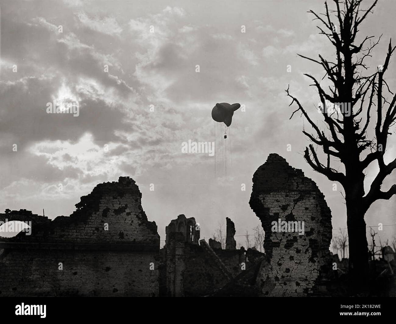 A British observation balloon above the ruins of Ypres, Belgium to spot enemy artillery in 1917. The balloons were filled with hydrogen gas, whose flammable nature led to the destruction of hundreds of balloons on both sides. Typically, balloons were tethered to a steel cable attached to a winch that reeled the gasbag to its desired height (usually 1,000-1,500 metres) and retrieved it at the end of an observation session. Stock Photo