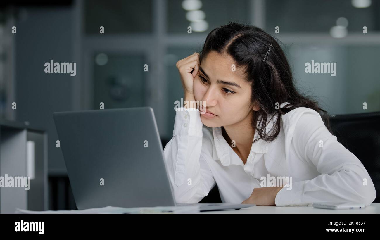 Bored sad lazy young indian woman manager sitting in office unmotivated uninterested in boring laptop work overworked tired sleepy businesswoman Stock Photo