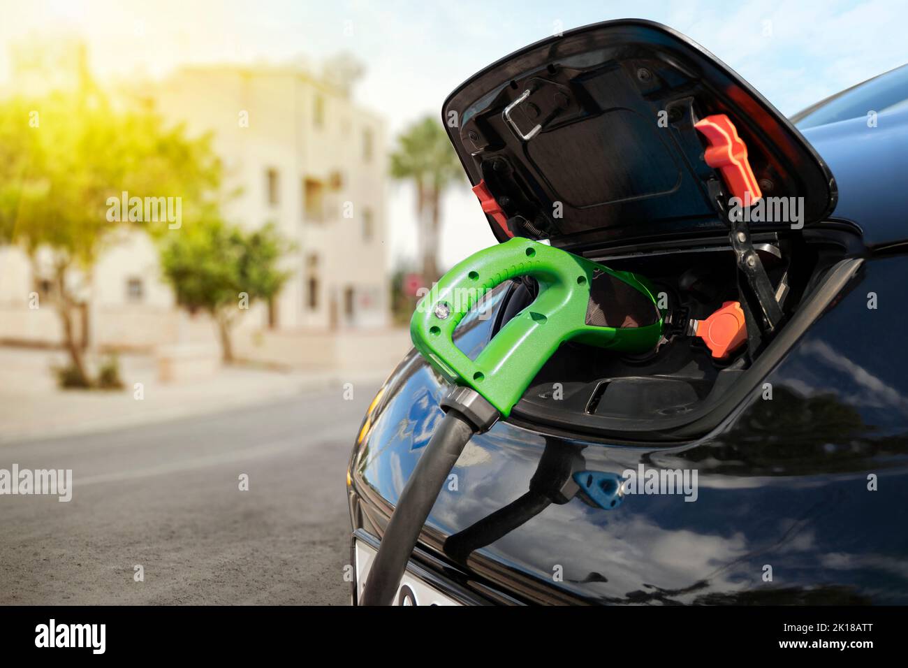 Electric car on charging spot in front of architecture buildings. Car sharing commuter charging station. Charging the batteries of an electric car on Stock Photo