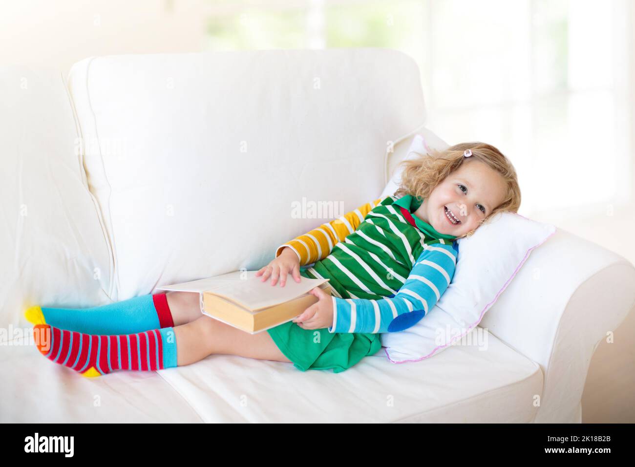 Child reading book. Kids read books. Little girl sitting on white couch ...
