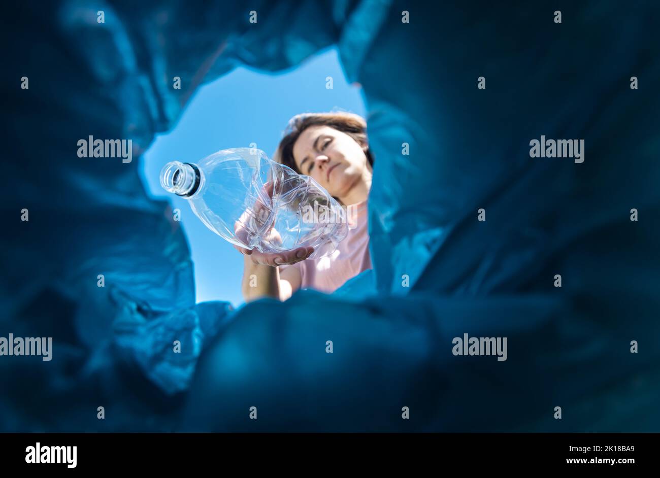 A woman throws a plastic bottle into the trash. Closeup from inside