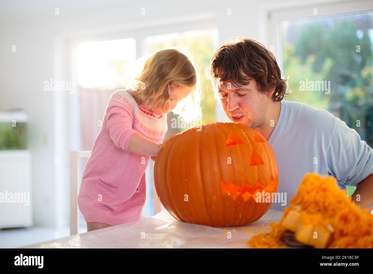 Father and child carving pumpkin for Halloween. Dad and little girl carve jack-o-lantern for trick or treat and home entrance decoration. Parents and Stock Photo