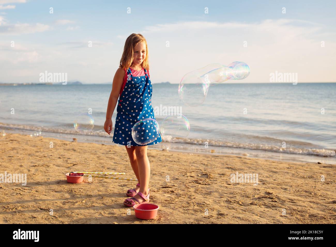 Kids blow bubbles at tropical beach. Child blowing soap bubble playing at sea. Family summer vacation with young kid. Outdoor beach activity for child Stock Photo
