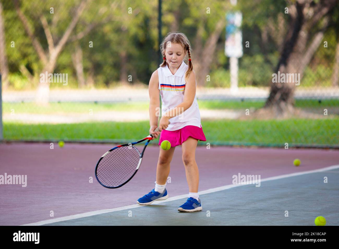 Child playing tennis on indoor court. Little girl with tennis racket and ball in sport club. Active exercise for kids. Summer activities for children. Stock Photo