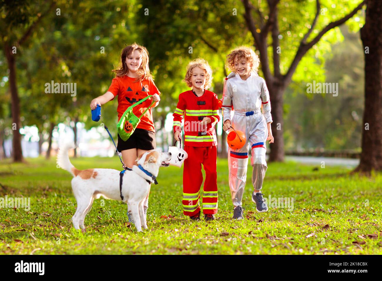 Kids trick or treat in Halloween costume. Children in colorful dress up with candy bucket on suburban street. Little boy and girl trick or treating wi Stock Photo