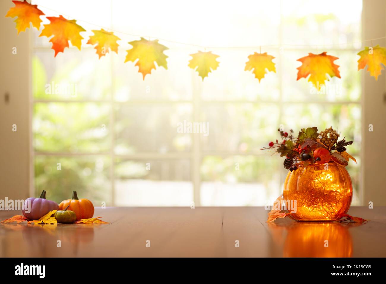 Autumn home decoration. Pumpkin lantern for Thanksgiving table setting. Orange leaves and flowers arrangement in living room. Fall colors in house dec Stock Photo