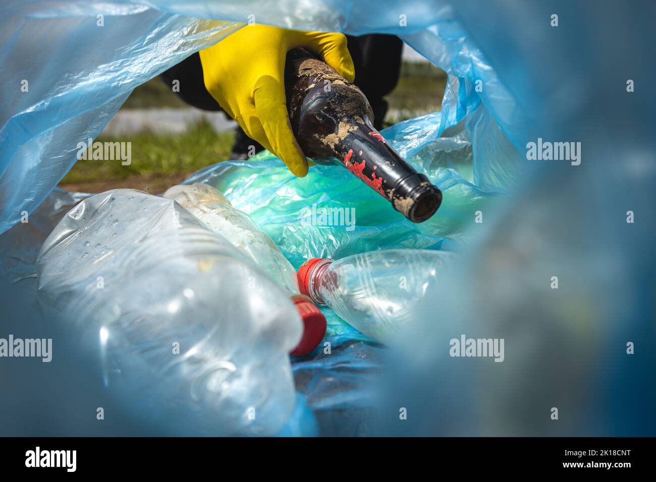 Closeup of a hand throwing garbage into a plastic bag. View from