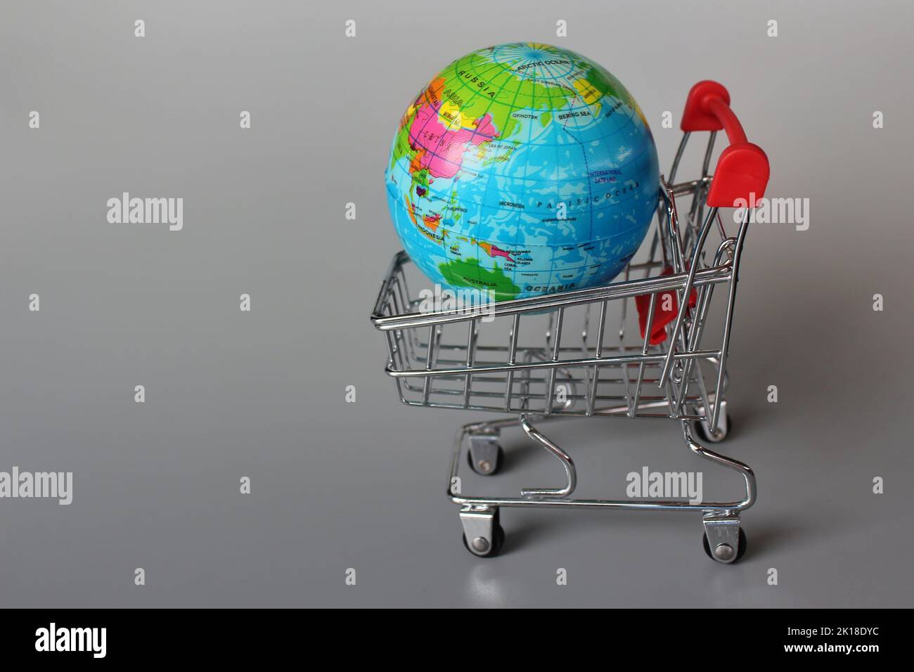 Global market, international market concept. Mini shopping trolley and globe on grey background Stock Photo