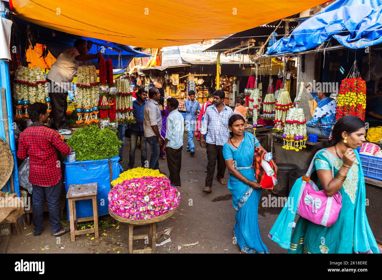 Mysore, Karnataka, India : Women walk past flower stalls at the Devaraja market. Stock Photo
