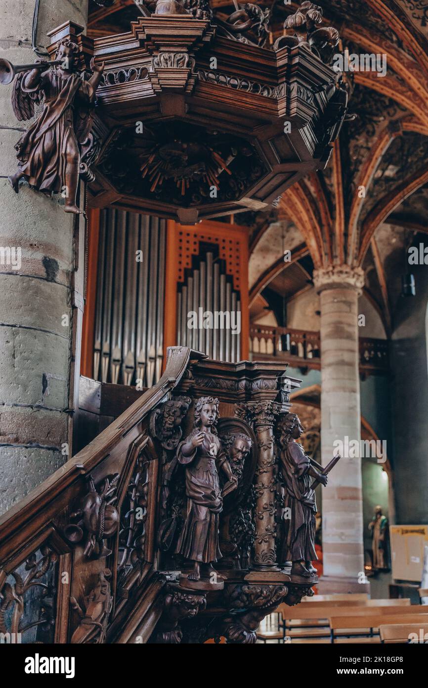 The interior of an old Eglise Saint-Pierre church with wooden statues in a vertical shot Stock Photo