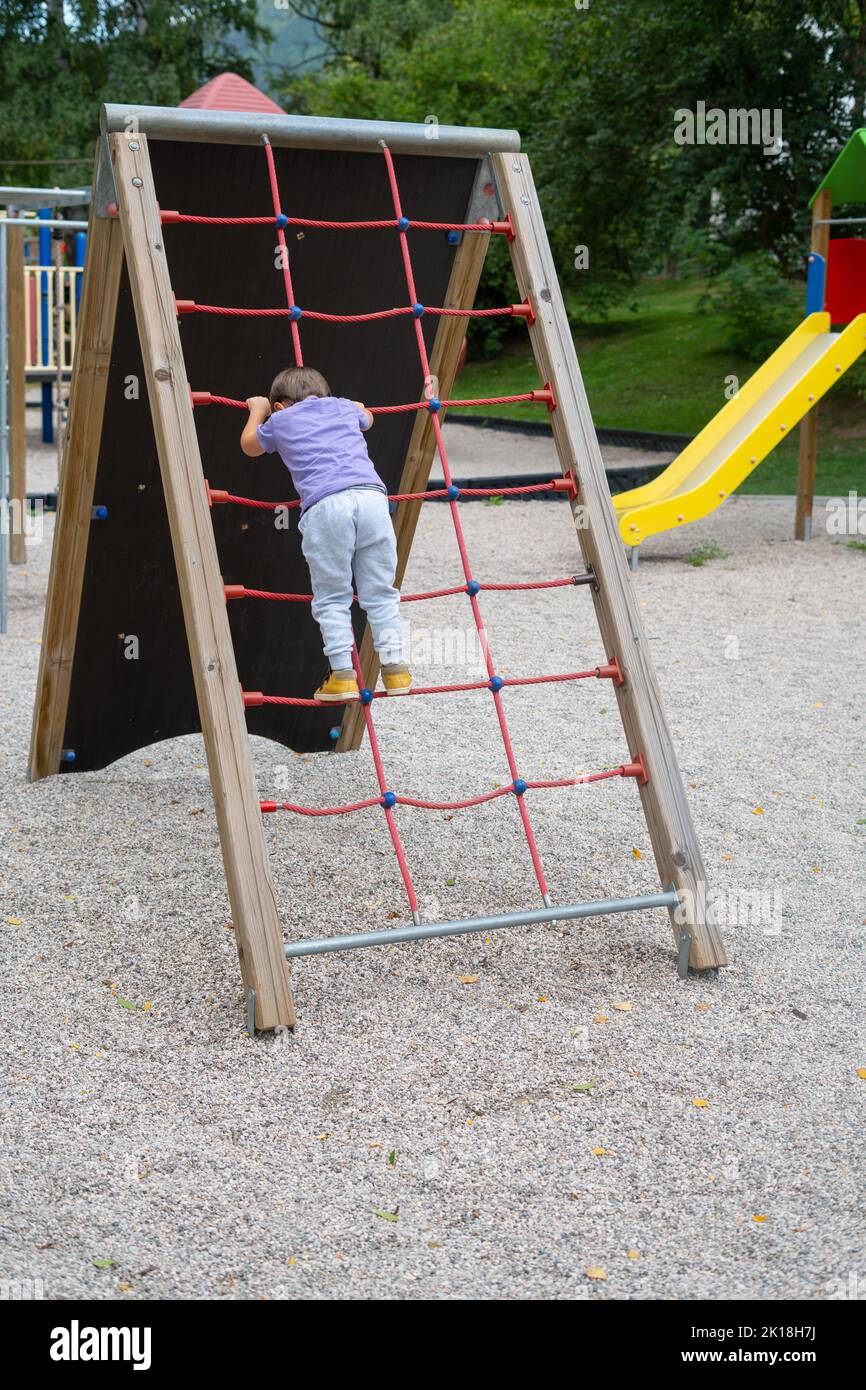 A boy (not recognizable) climbs a rope ladder in a children's park