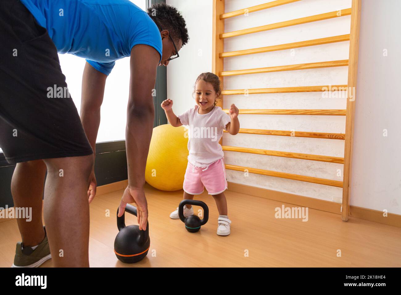 Little kid lifting kettlebell with father Stock Photo