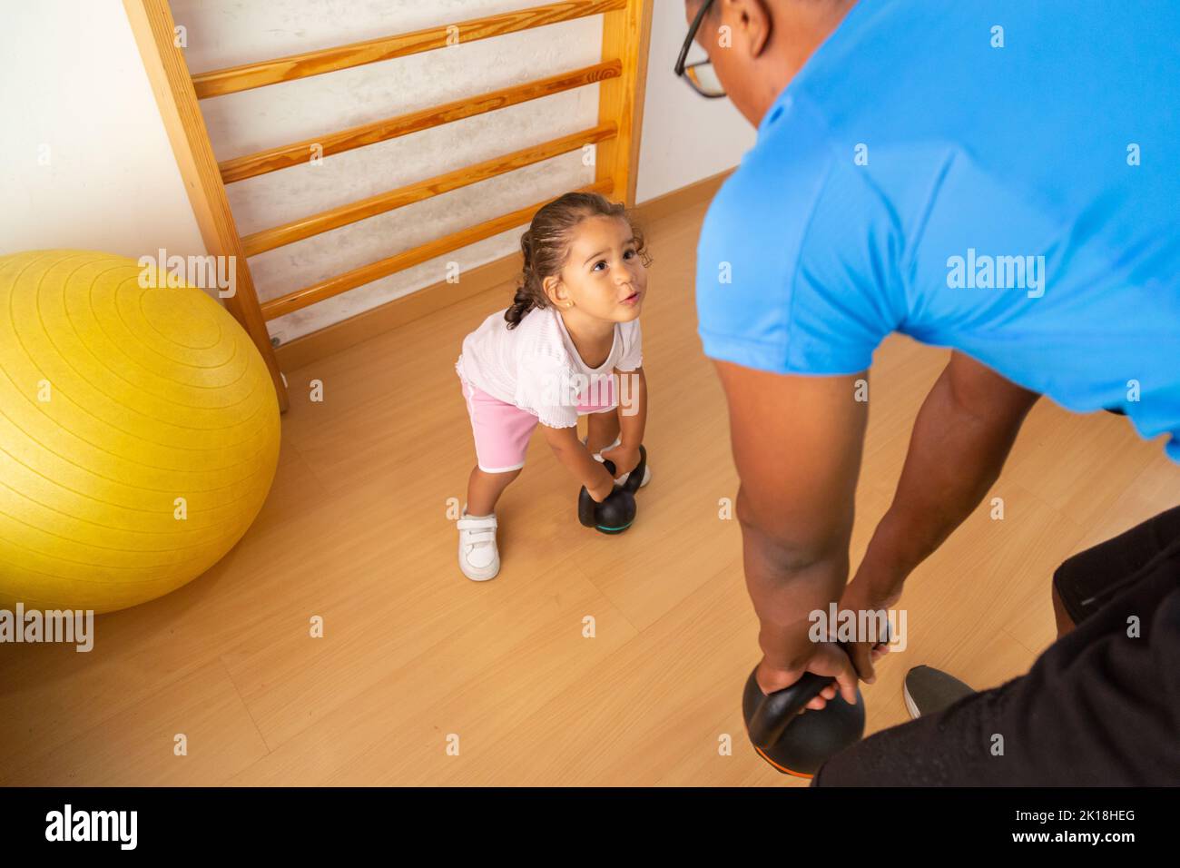 Little kid lifting kettlebell with father Stock Photo